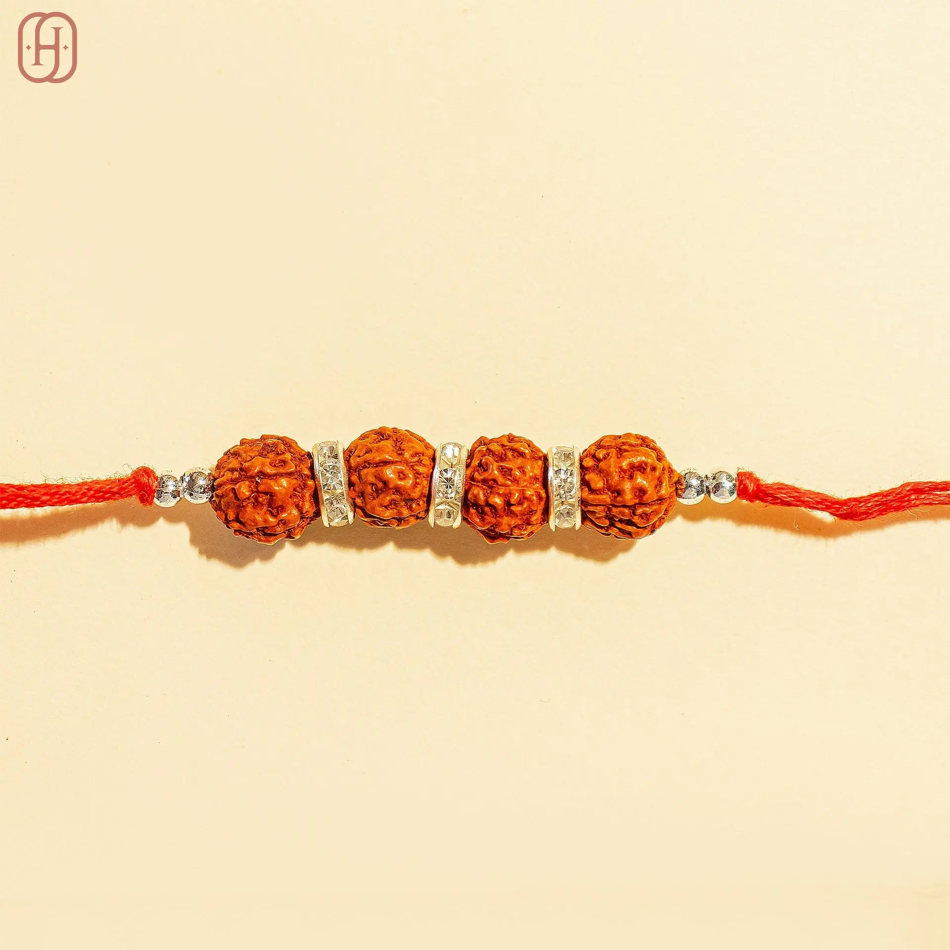 Traditional rudraksha rakhi online with four rudraksha beads and silver embellishments on red thread