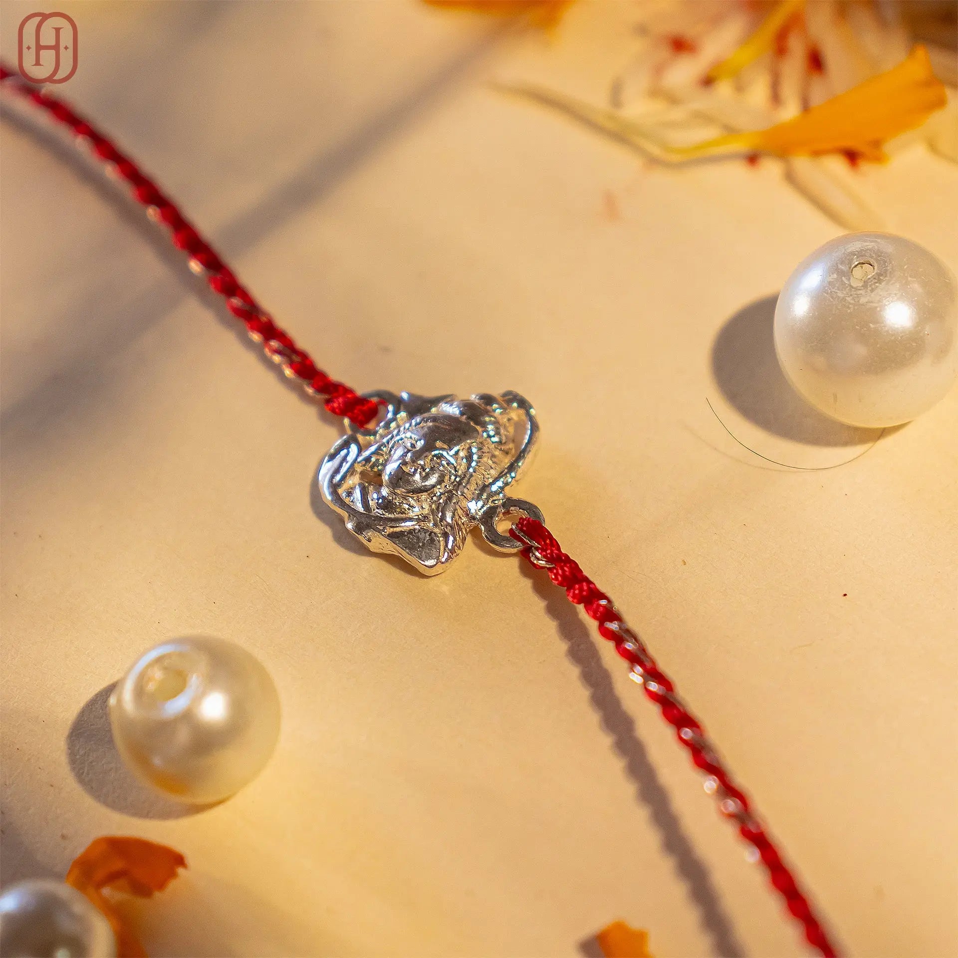 Shiv ji silver rakhi online with red thread and silver pendant from Hardik Jewels displayed with decorative pearls