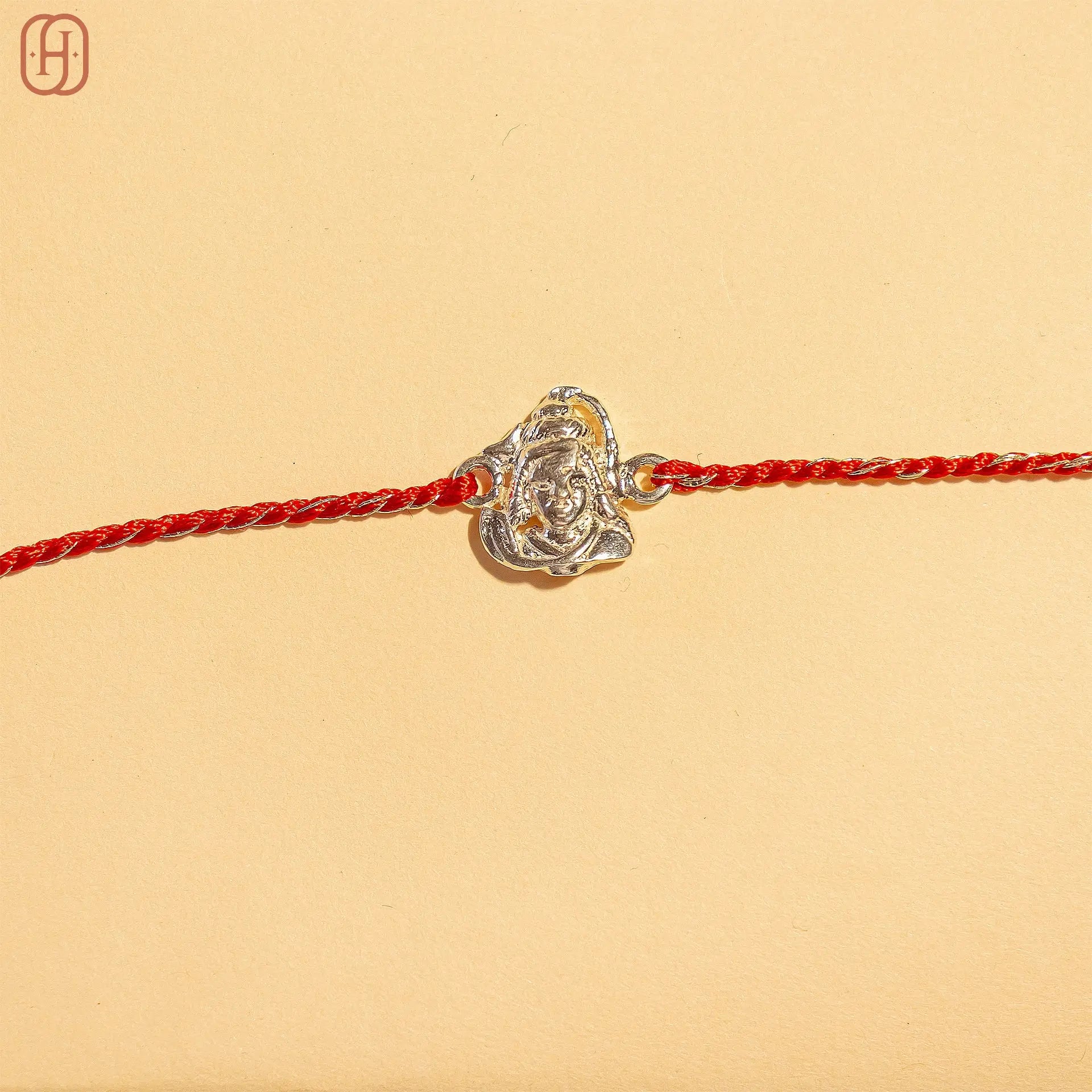Shiv ji silver rakhi online with detailed silver centerpiece and red braided thread by Hardik Jewels