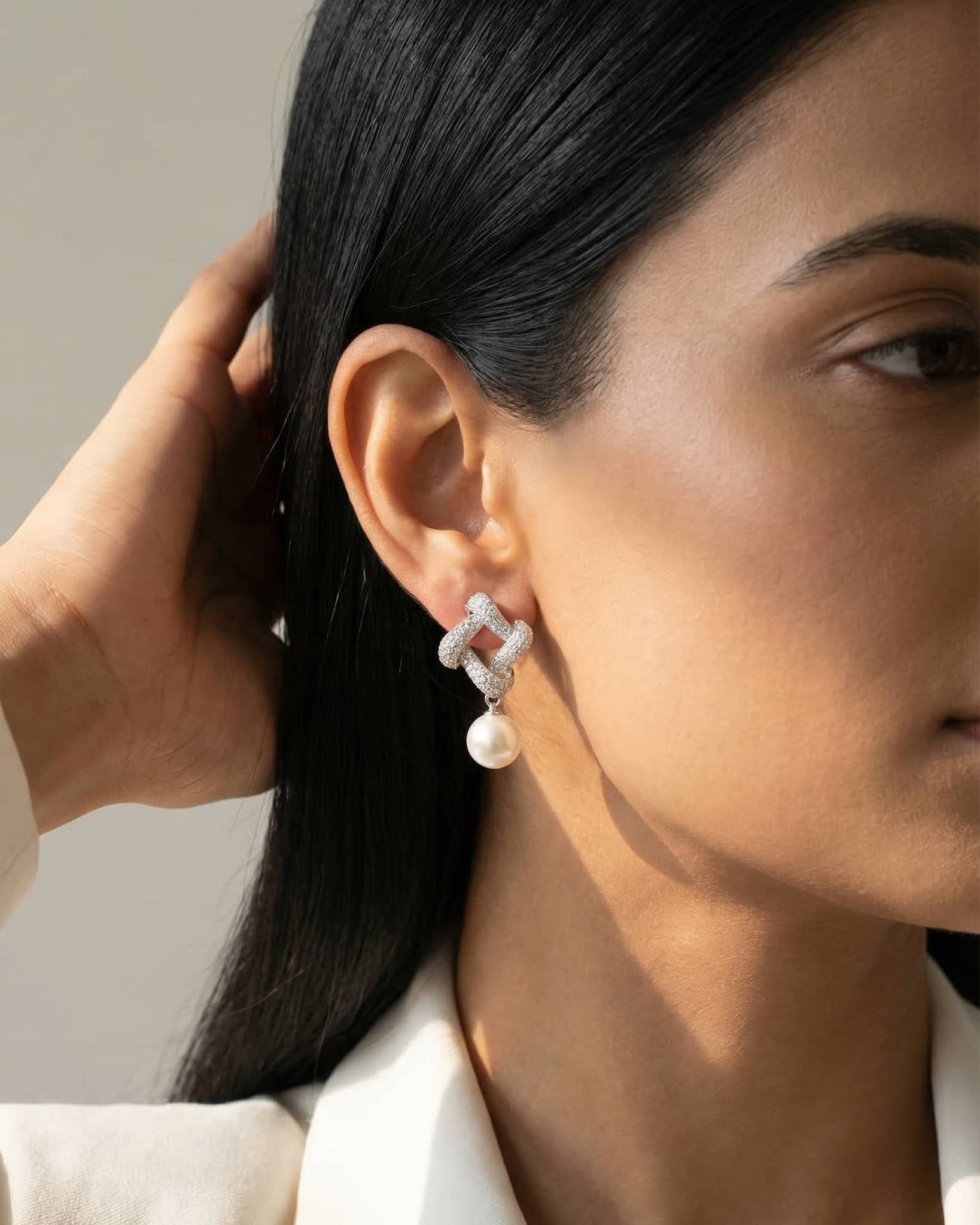 Beautiful woman wearing 92.5 sterling silver cz knot and pearl drop earrings for a sophisticated look.