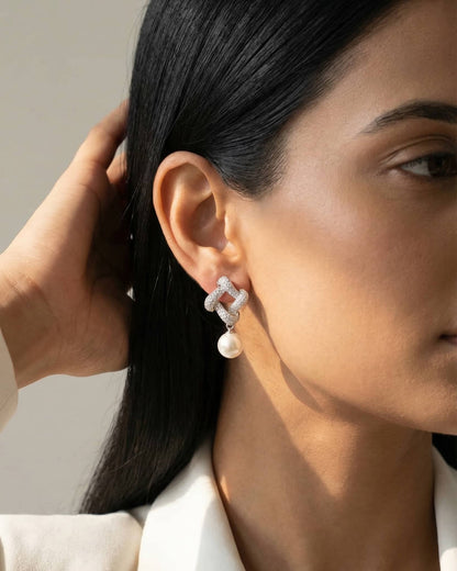 Beautiful woman wearing 92.5 sterling silver cz knot and pearl drop earrings for a sophisticated look.