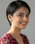 Smiling beautiful woman wearing elegant silver ruby pink cz teardrop pave stud earrings, paired with a maroon floral outfit.