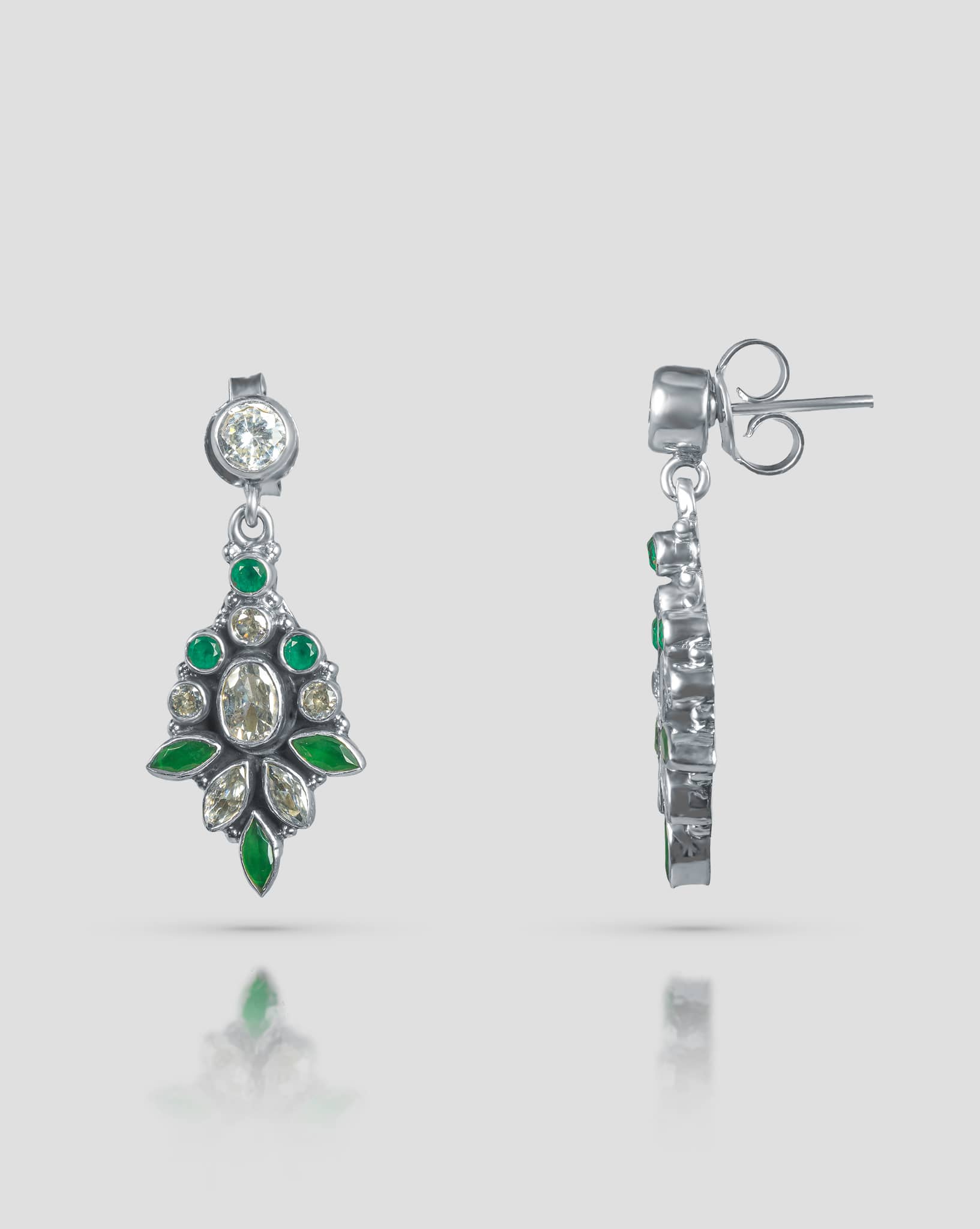 Floating angled shot of elegant 92.5 sterling silver antique chandelier earrings featuring an intricate mix of oval, round, and marquise cut green and clear cz stones.
