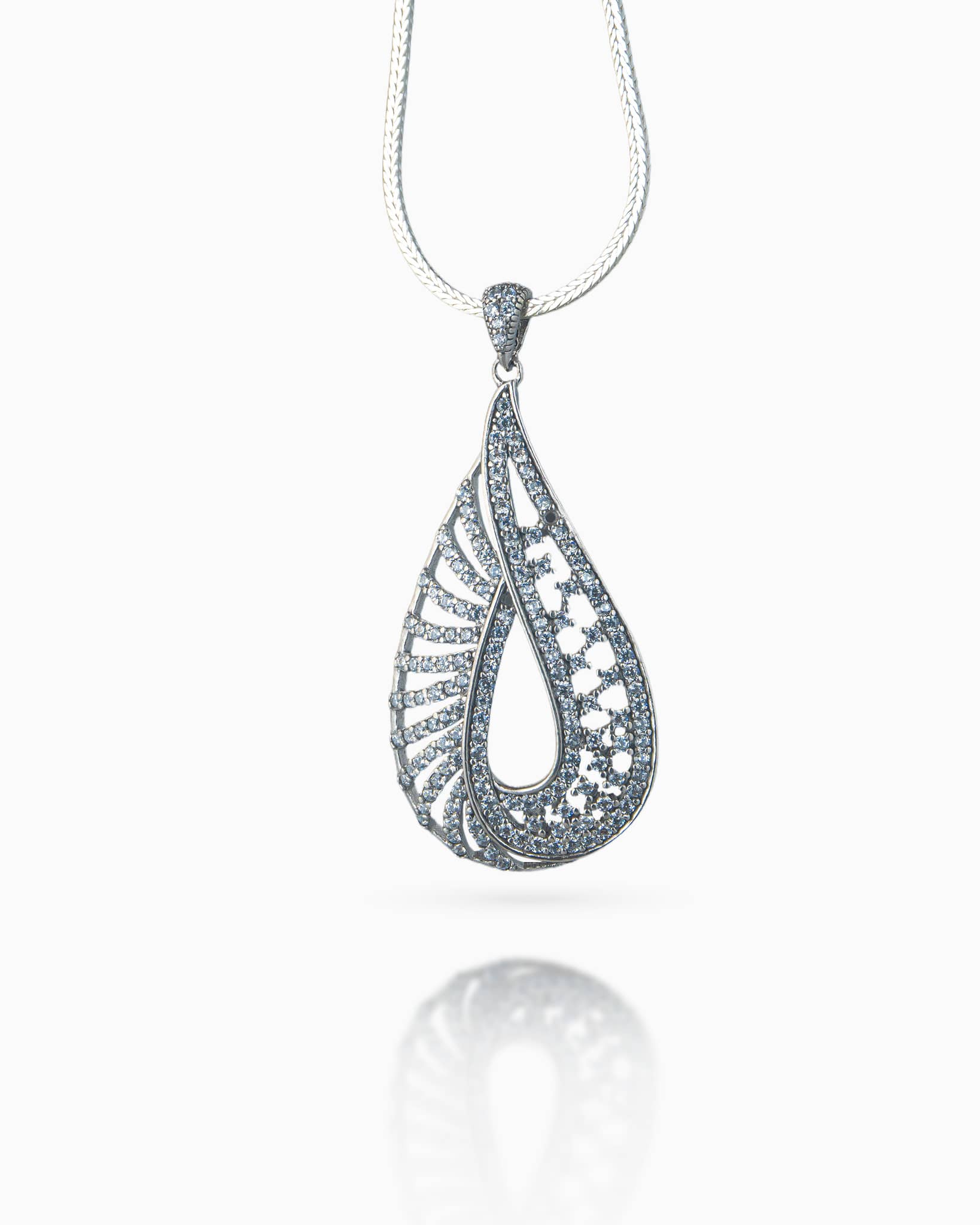 Close up of a silver cz teardrop pendant showing intricate asymmetrical lattice detailing and a sparkling micro-pave finish.