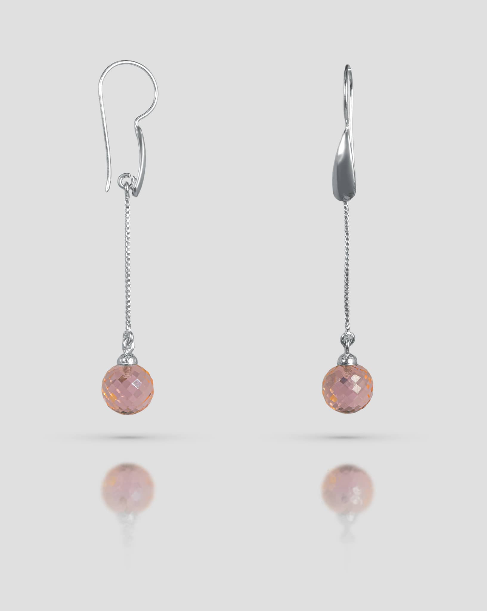 Floating angled shot of 92.5 sterling silver long dangle earrings featuring a fine silver chain and a faceted pink spherical stone drop.