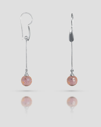 Floating angled shot of 92.5 sterling silver long dangle earrings featuring a fine silver chain and a faceted pink spherical stone drop.