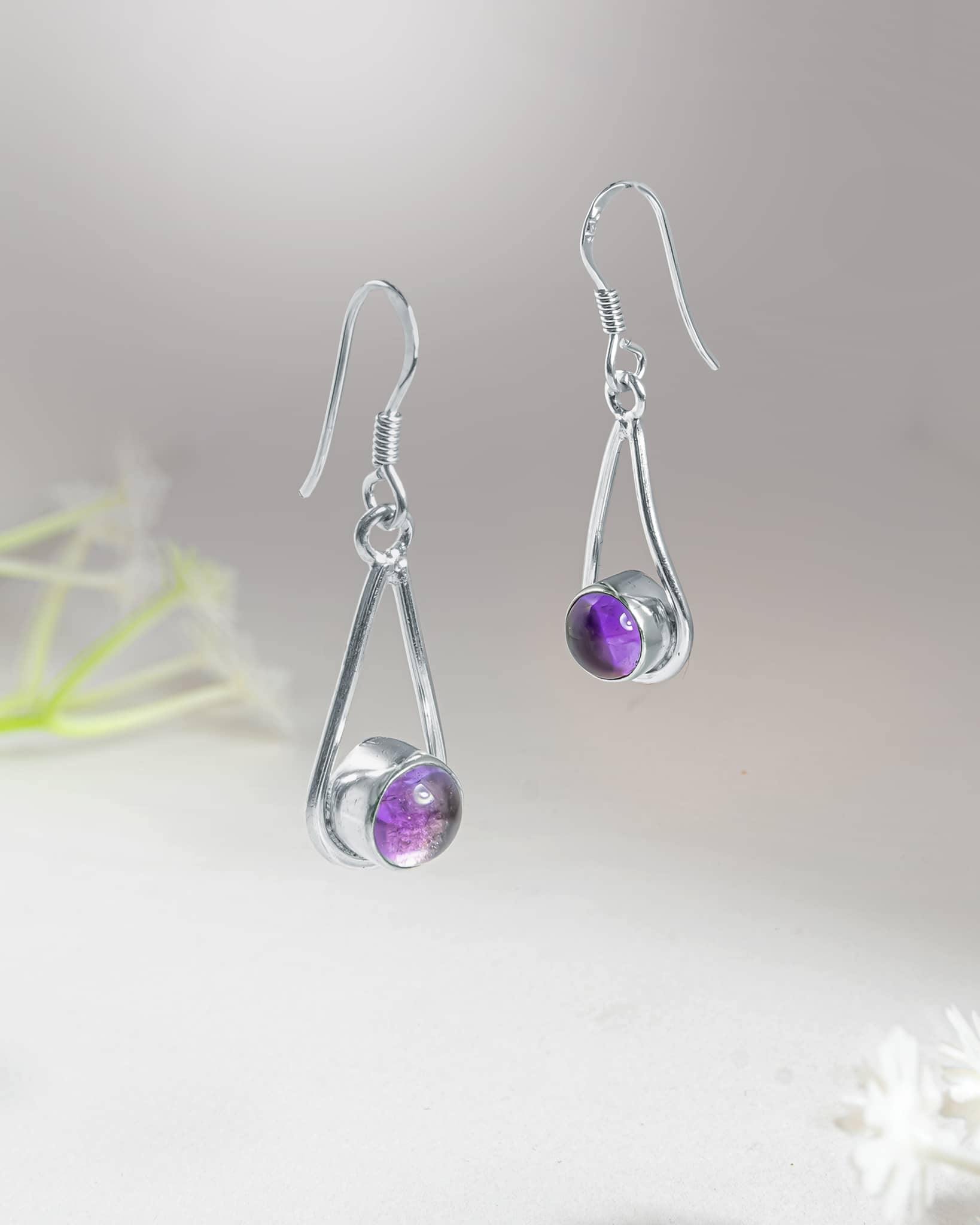 Front and side profile view of silver purple cabochon drop earrings showcasing the high polish open frame, bezel set stone, and french wire closure.