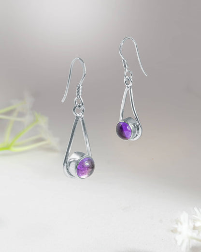 Front and side profile view of silver purple cabochon drop earrings showcasing the high polish open frame, bezel set stone, and french wire closure.