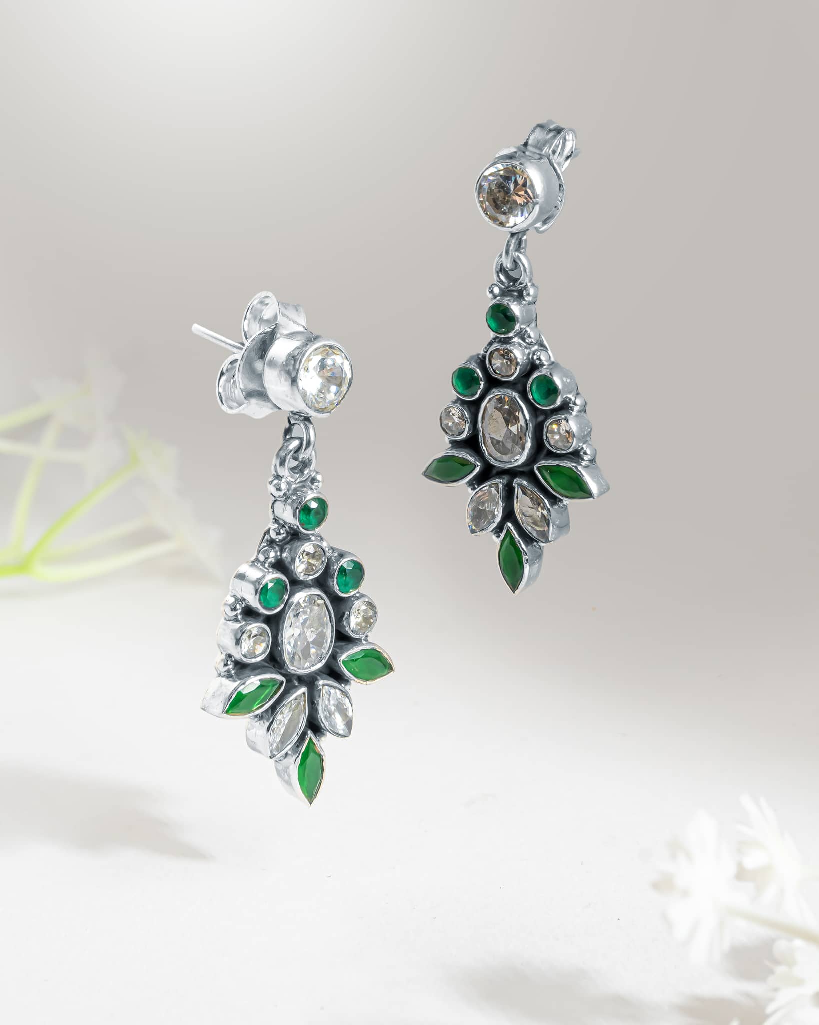 Front and side profile view of vintage silver green and clear cz drop earrings showcasing the dark oxidized finish, floral stone arrangement, and push-back closure.