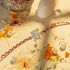 92.5 silver hanuman rakhi with red and white braided thread decorated with flowers, rice, and pearls